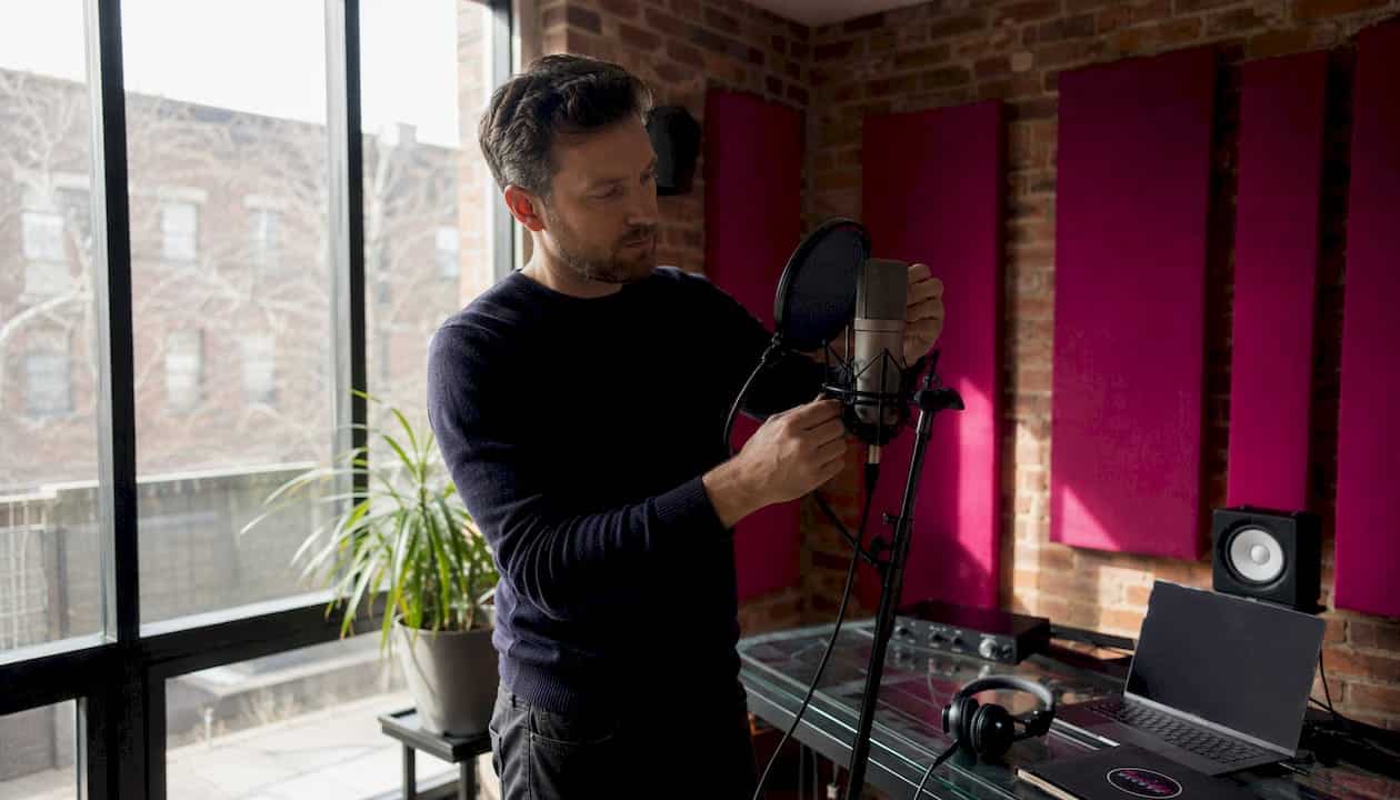 Engineer adjusting mic with pop filter in home studio