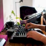 Hands adjusting audio equipment in home studio