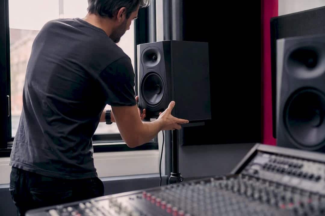 Hands adjusting studio monitor position