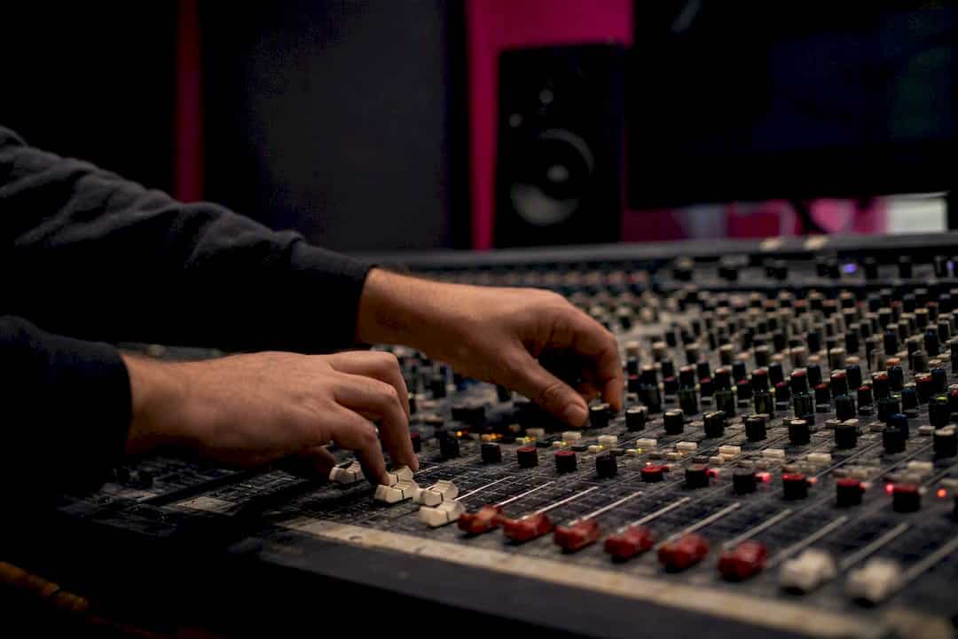 Hands adjusting mastering controls on audio desk